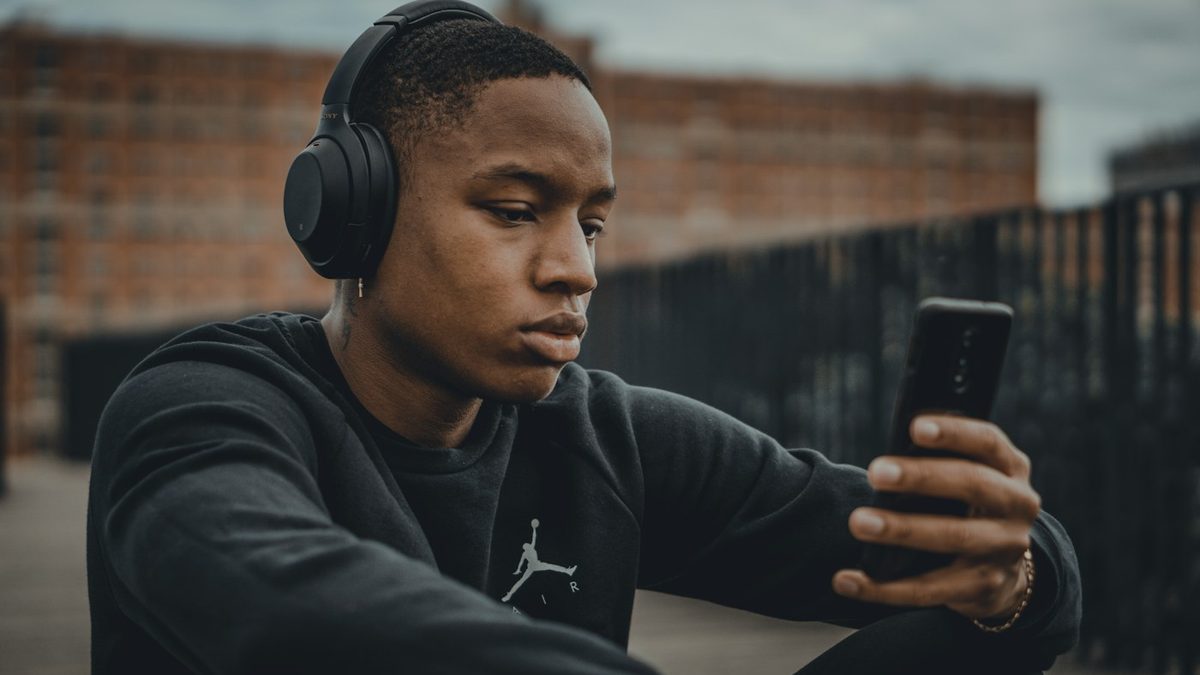 Joven con audífonos escuchando radio online en su celular